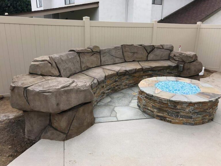 Curved faux rock bench wrapping a stacked-stone fire pit on a flagstone patio